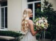Gorgeous bride with wedding flowers boquet posing outdoors, against luxury house